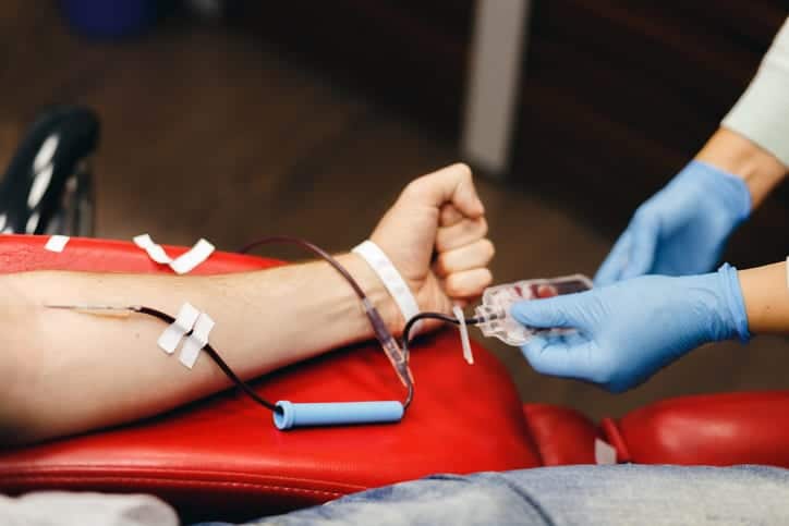 Nurse collecting blood sample using a needle